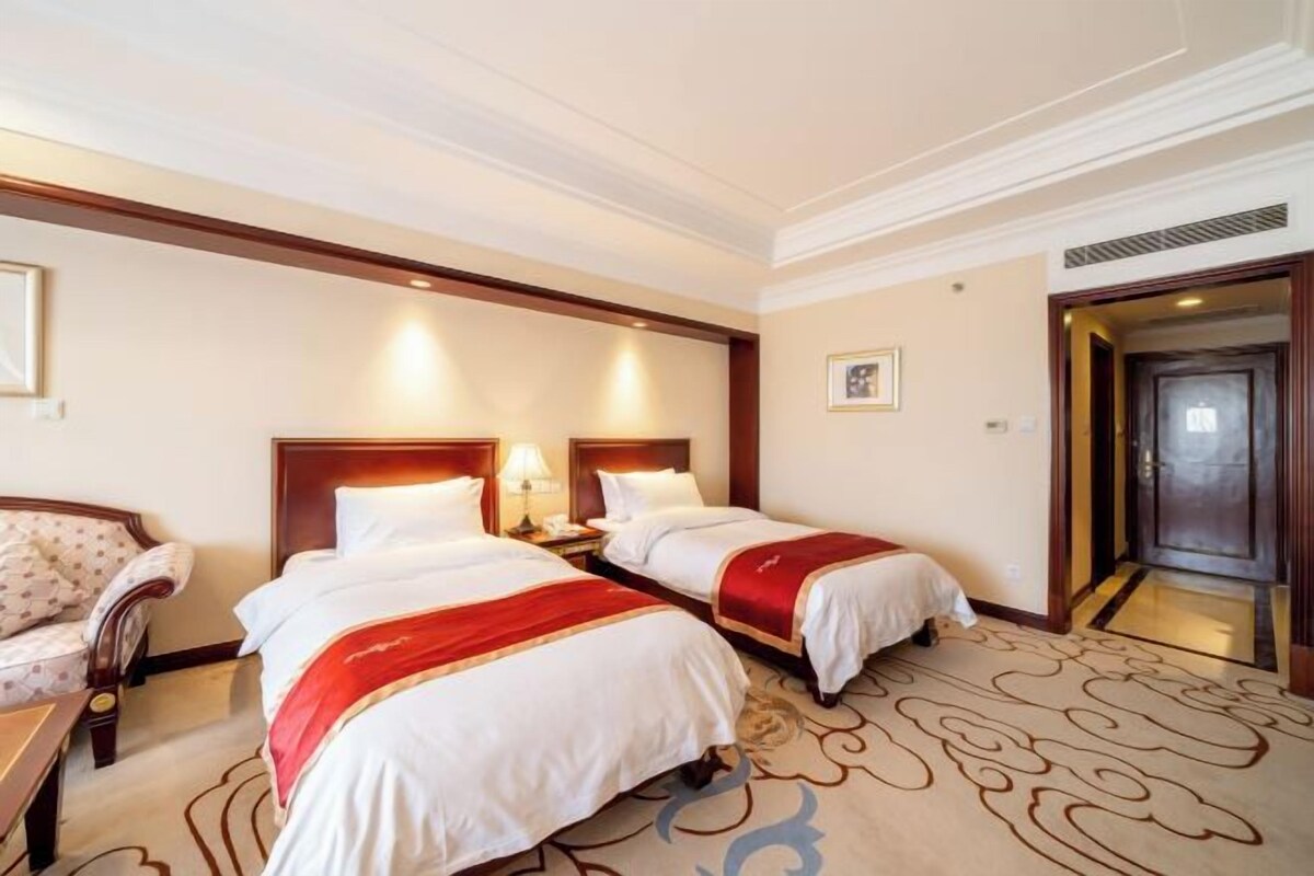 Une chambre d’hôtel avec deux lits, une chaise, une table de chevet et une porte.
