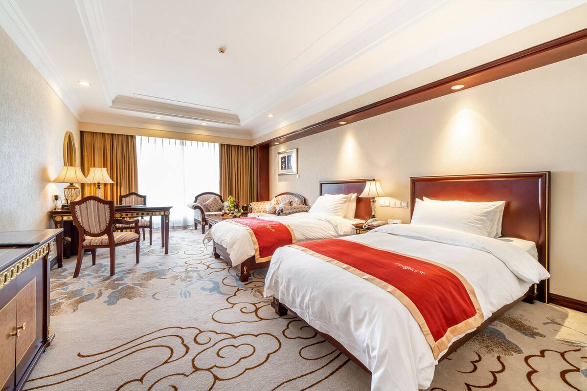 Une chambre d’hôtel avec deux lits, un bureau et une chaise.