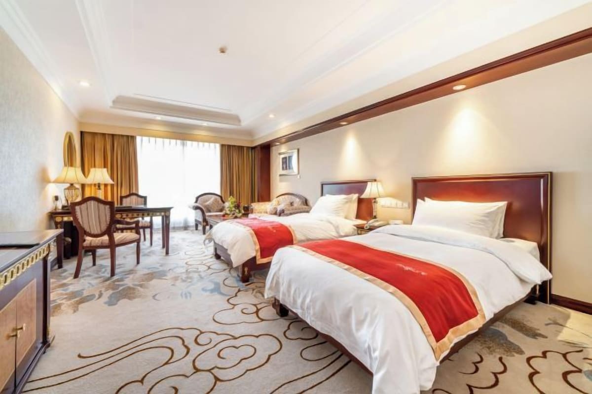 Ein Hotelzimmer mit zwei Betten, einem Schreibtisch und einem Stuhl.