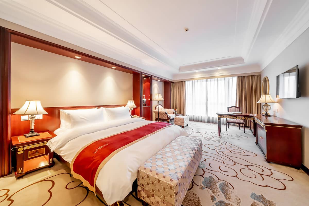Une chambre d’hôtel avec un grand lit, des tables de chevet, un bureau et une chaise.
