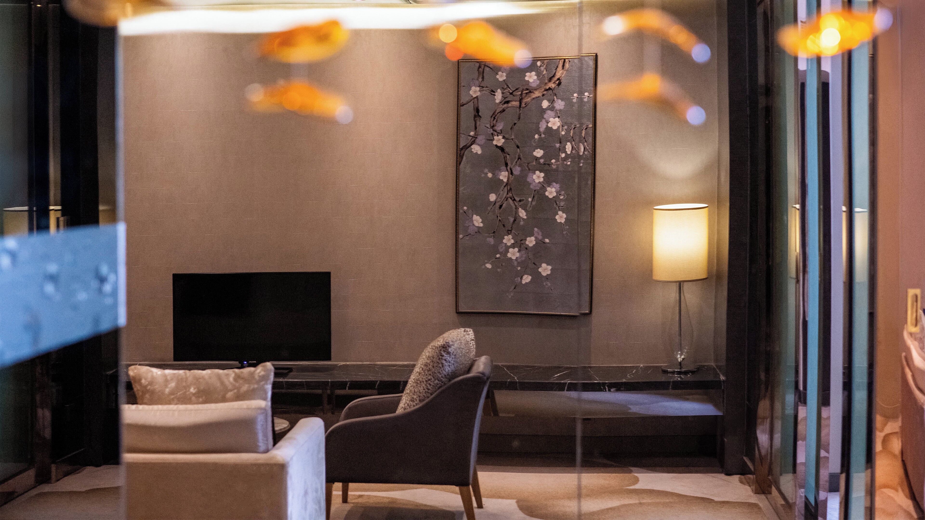 Een moderne woonkamer met een flatscreen televisie, een bank, een stoel, een salontafel en een wandlamp.