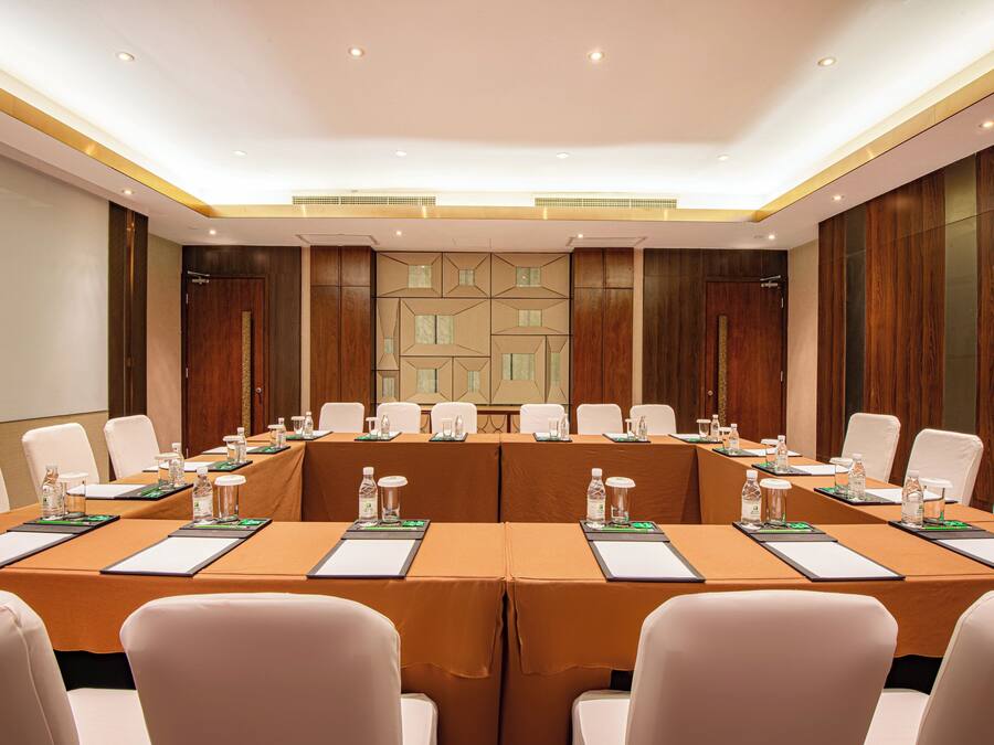 A conference room with a long table, white chairs, and water bottles on place settings.