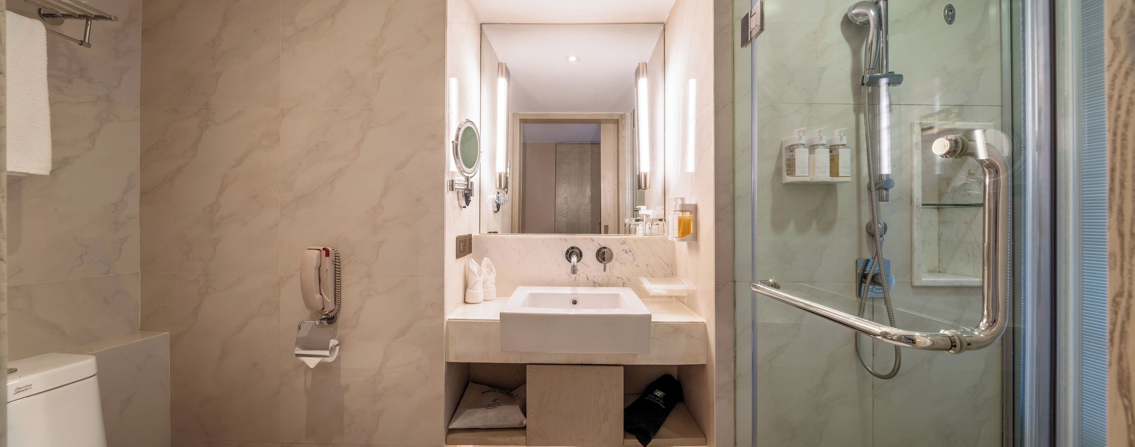 A modern bathroom with a marble sink, a glass-enclosed shower, and a towel rack.