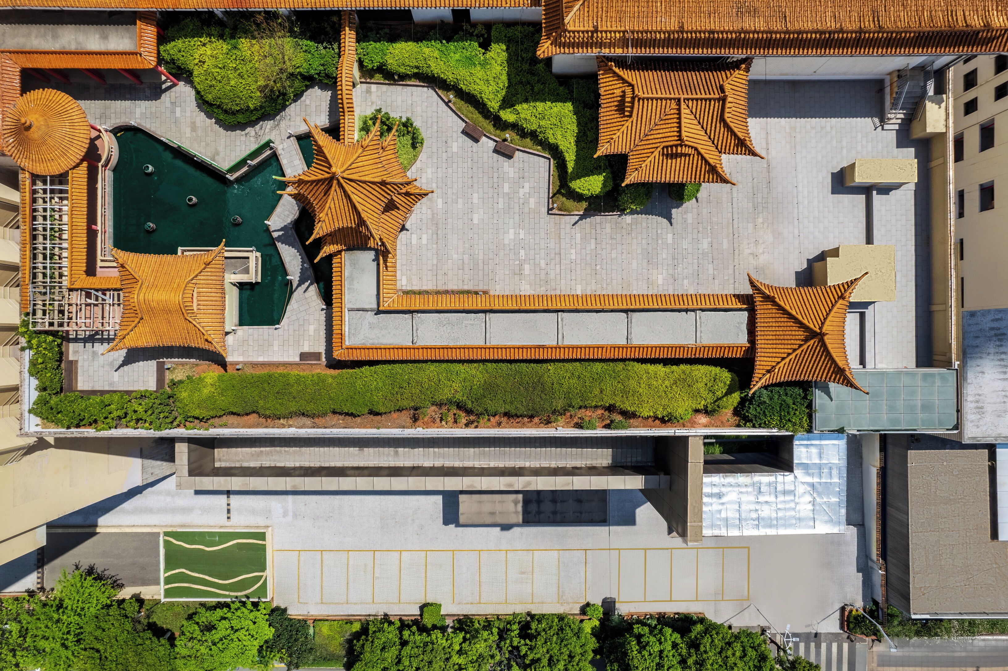 Luchtbeeld van een hotel met een zwembad op het dak, ligbedden en een gazon.