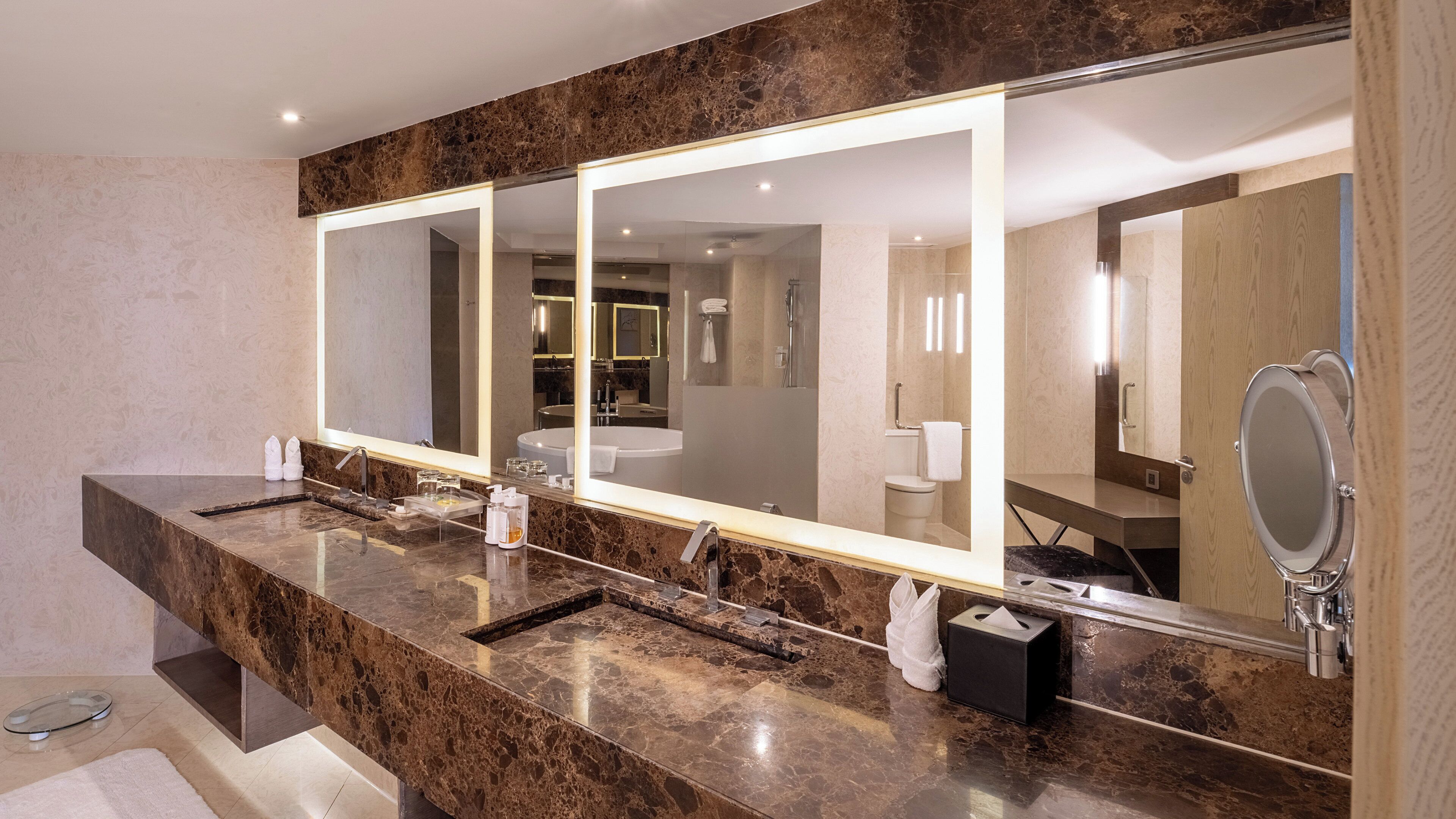 A modern bathroom with a marble vanity, a large mirror, and a separate sink.