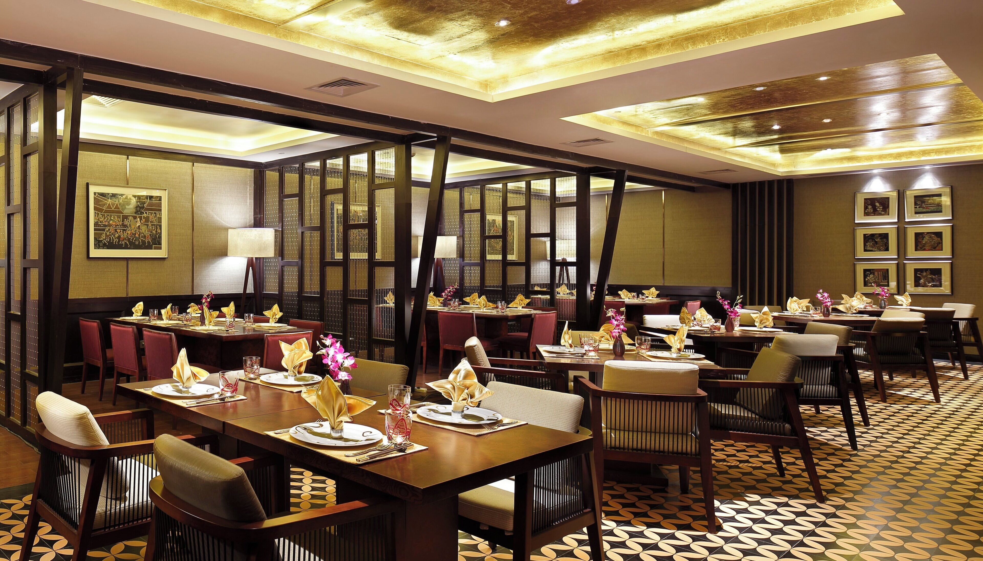 A hotel dining area with multiple tables set for guests, featuring traditional decor and a patterned floor.
