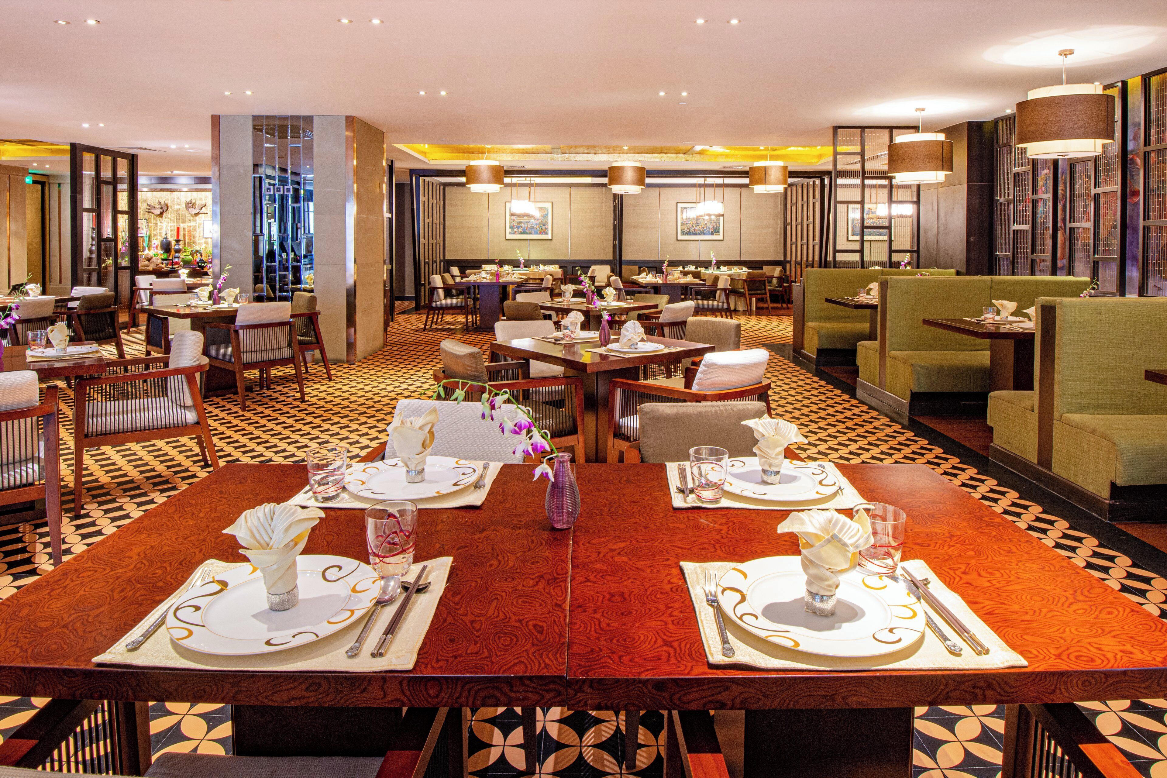 A restaurant with multiple dining tables, chairs, and a patterned floor.