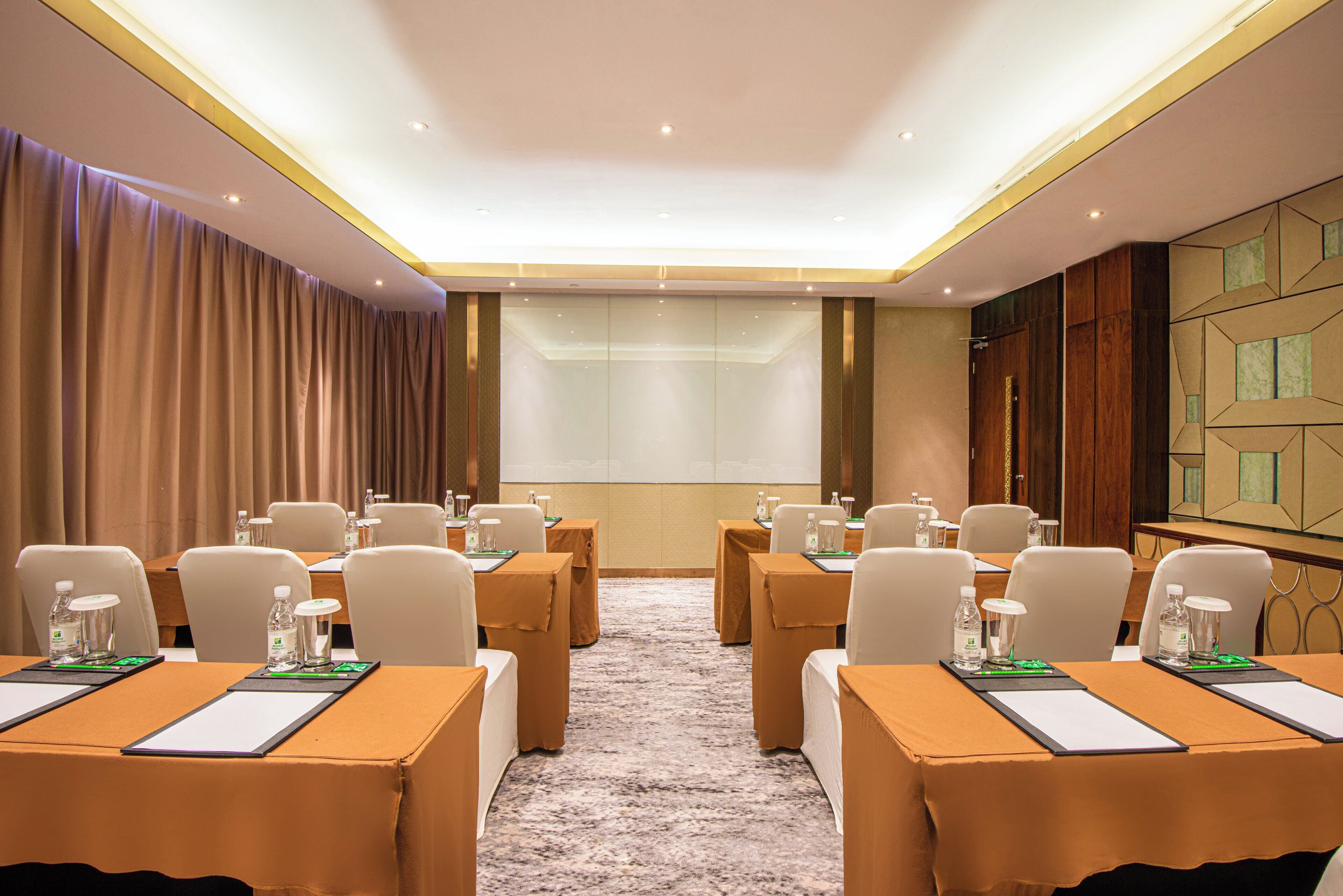 A conference room with tables, chairs, and a projection screen.