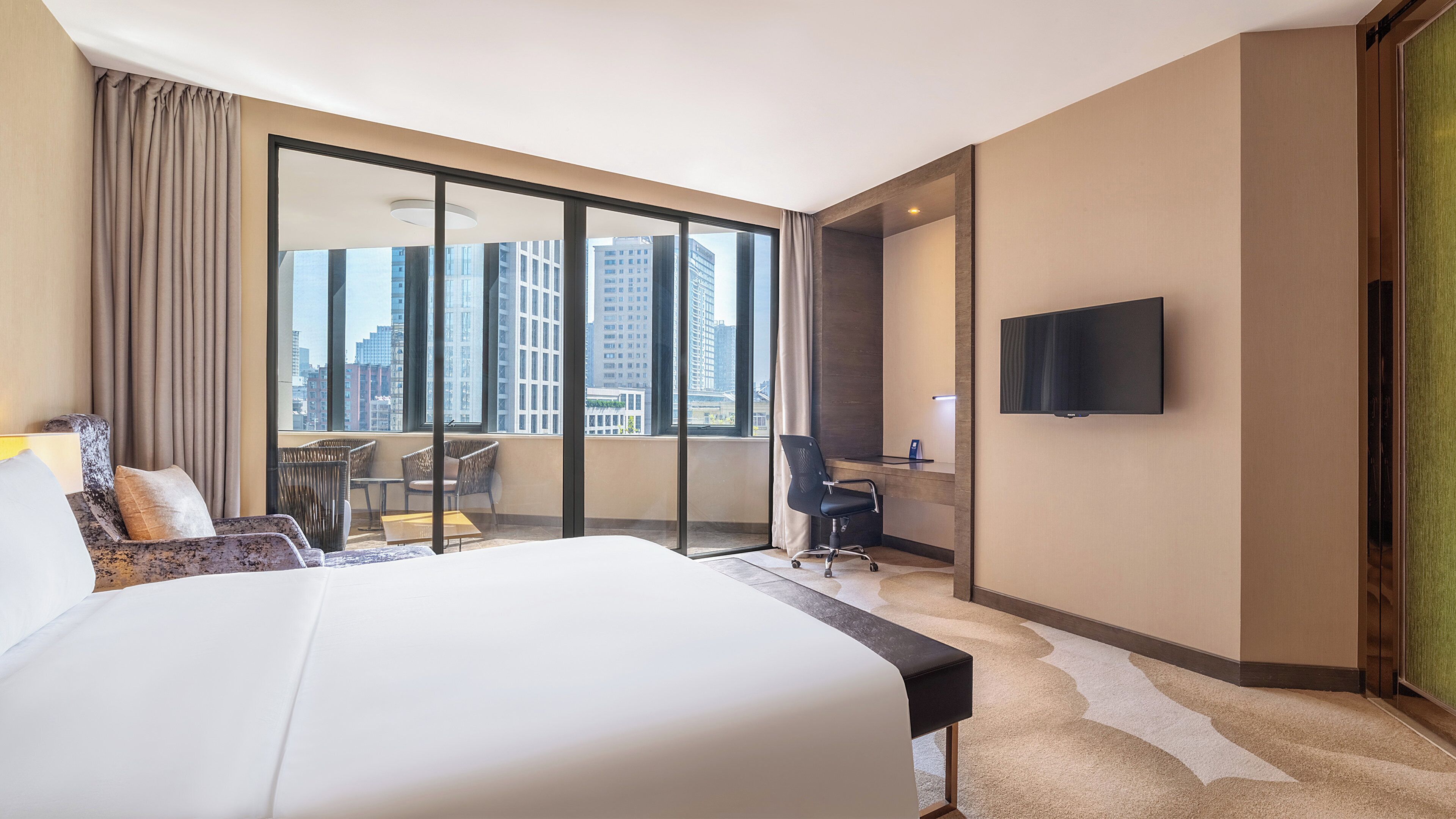 Une chambre d’hôtel avec un grand lit, un bureau, une chaise et un téléviseur.
