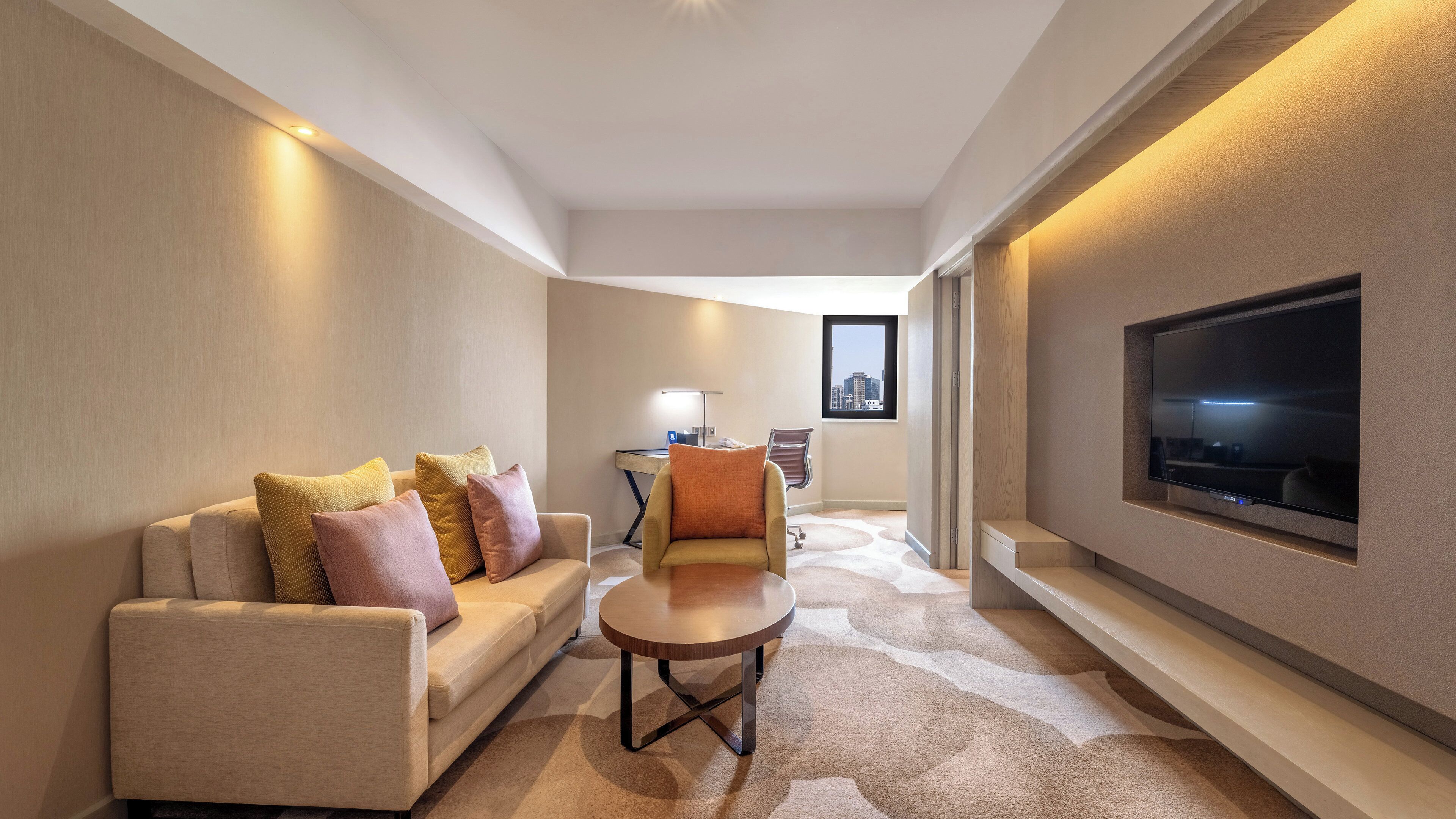 Una camera d'albergo moderna con divano, poltrona e televisore a parete.