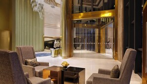 A lobby with seating, a reception desk, and a glass elevator. - Holiday Inn Kunming City Centre by IHG (Kunming)