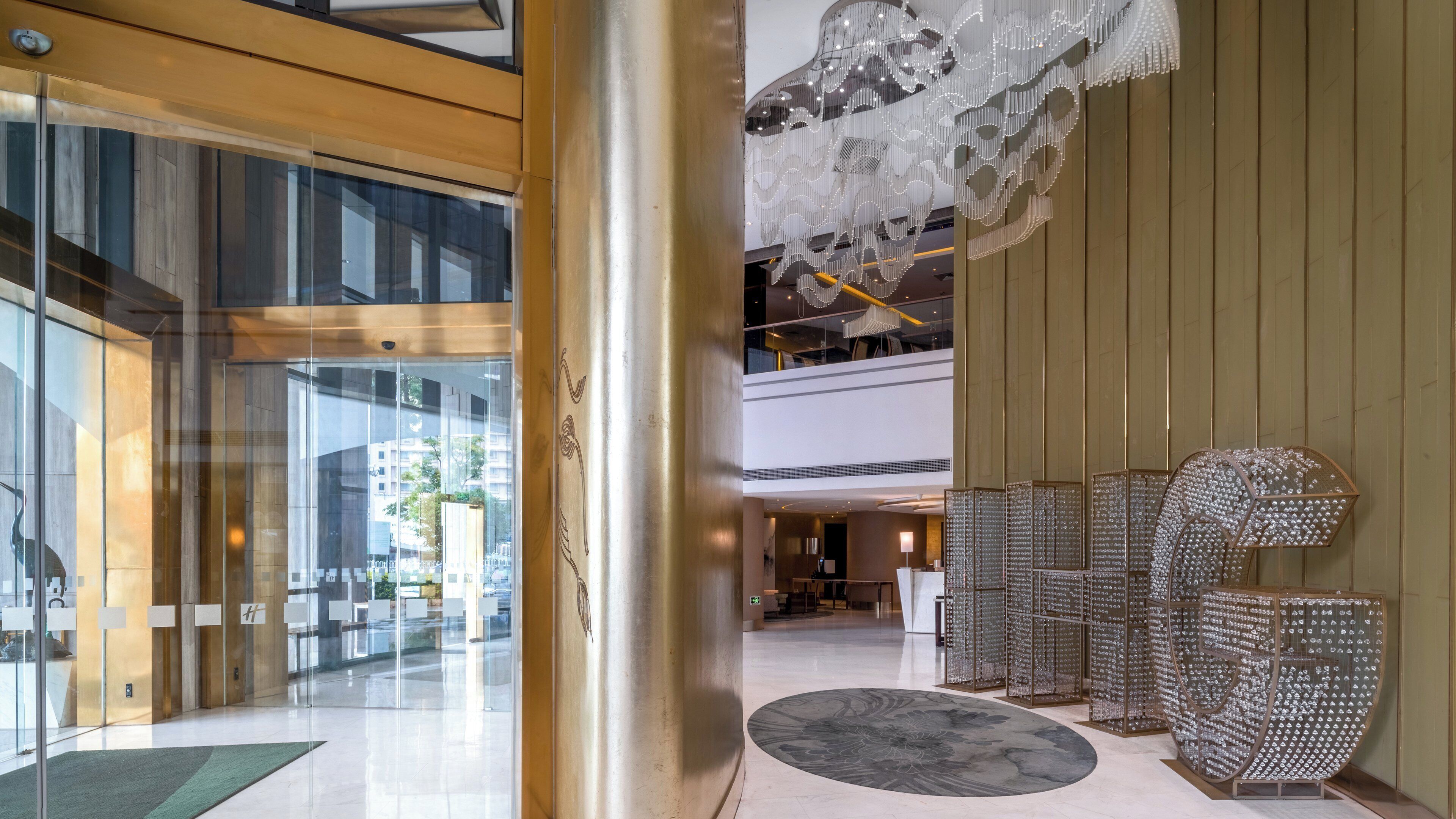 A modern hotel lobby with a glass entrance, a central column, and a decorative seating area.