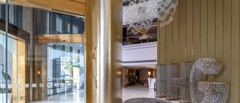 A modern hotel lobby with a glass entrance, a central column, and a decorative seating area.