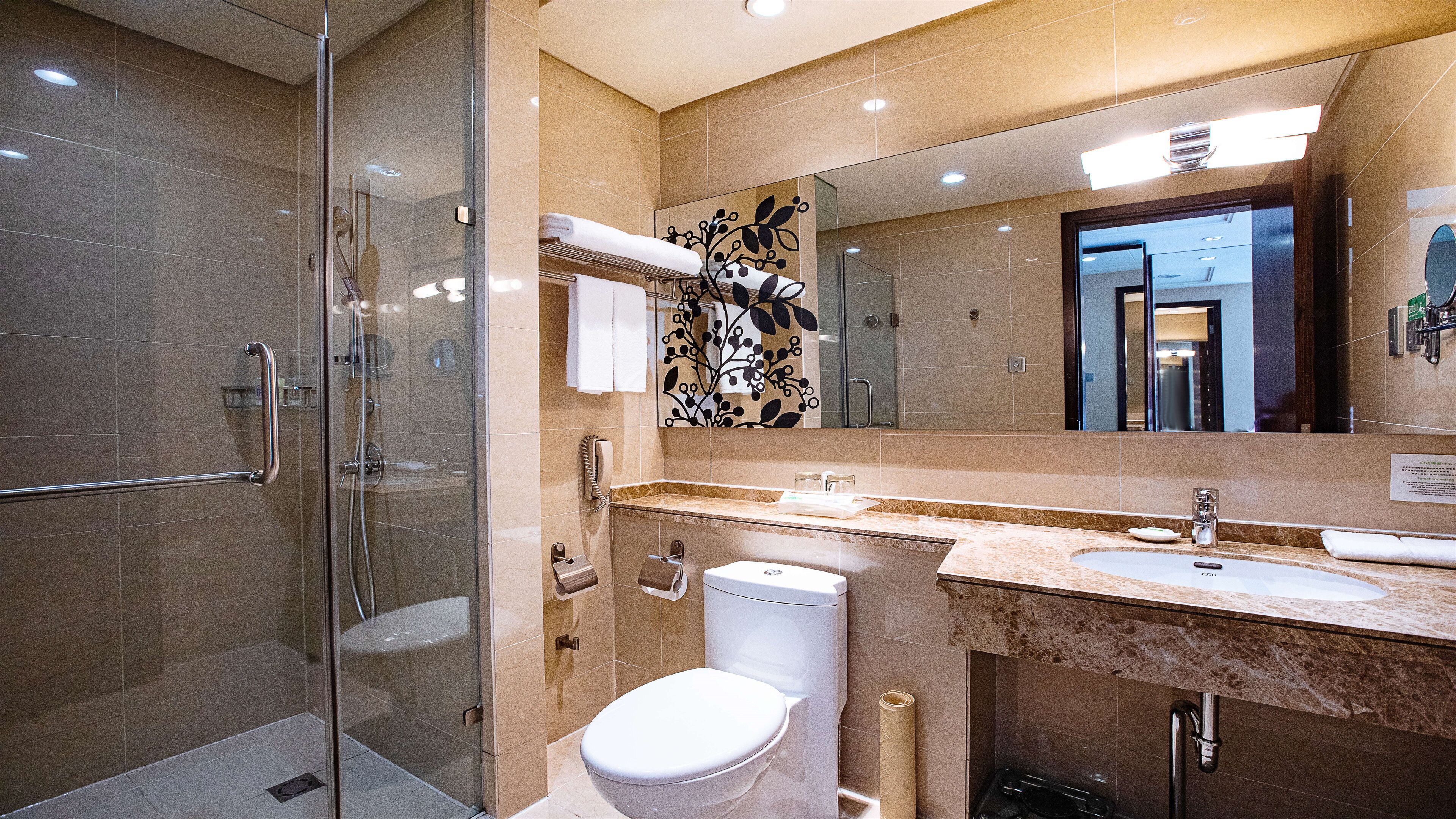 A modern bathroom with a glass-enclosed shower, a toilet, and a sink with a marble countertop.