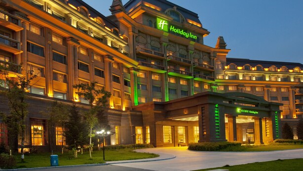 A multi-story hotel with a prominent green sign reading "Holiday Inn." - Holiday Inn Mudanjiang by IHG (Mudanjiang)