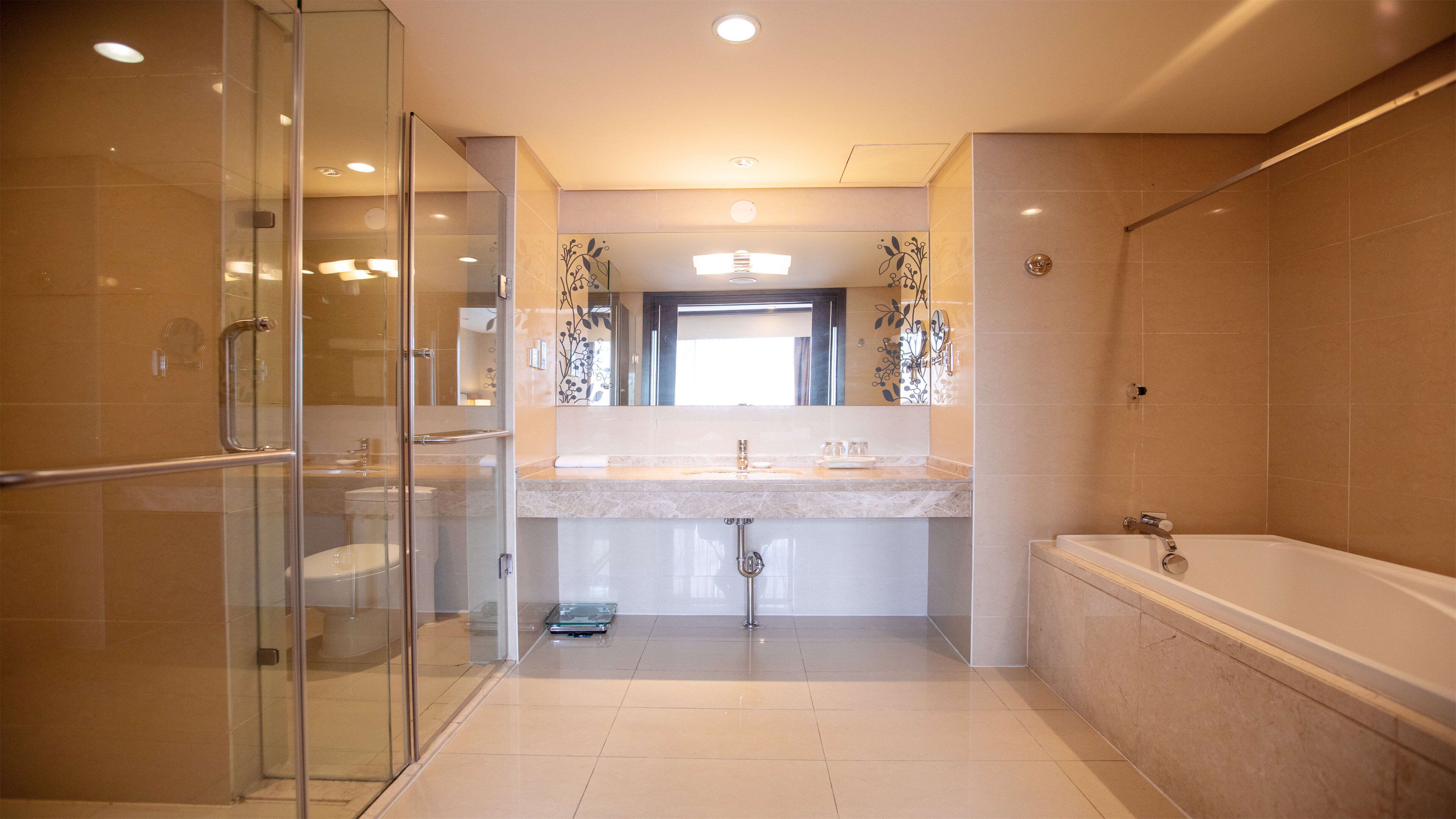 Een moderne badkamer met een glazen douchecabine, een grote spiegel en een bad.