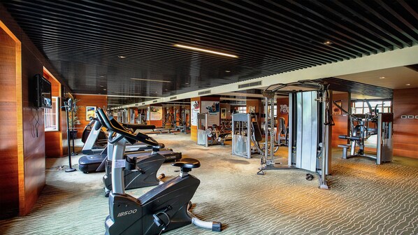 Un gimnasio con diverso equipo de ejercicio, incluyendo cintas de correr y máquinas de pesas.