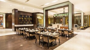 A spacious dining area with multiple tables and chairs, a bar area with shelves of bottles, and a modern interior design. - Holiday Inn Mudanjiang by IHG (Mudanjiang)