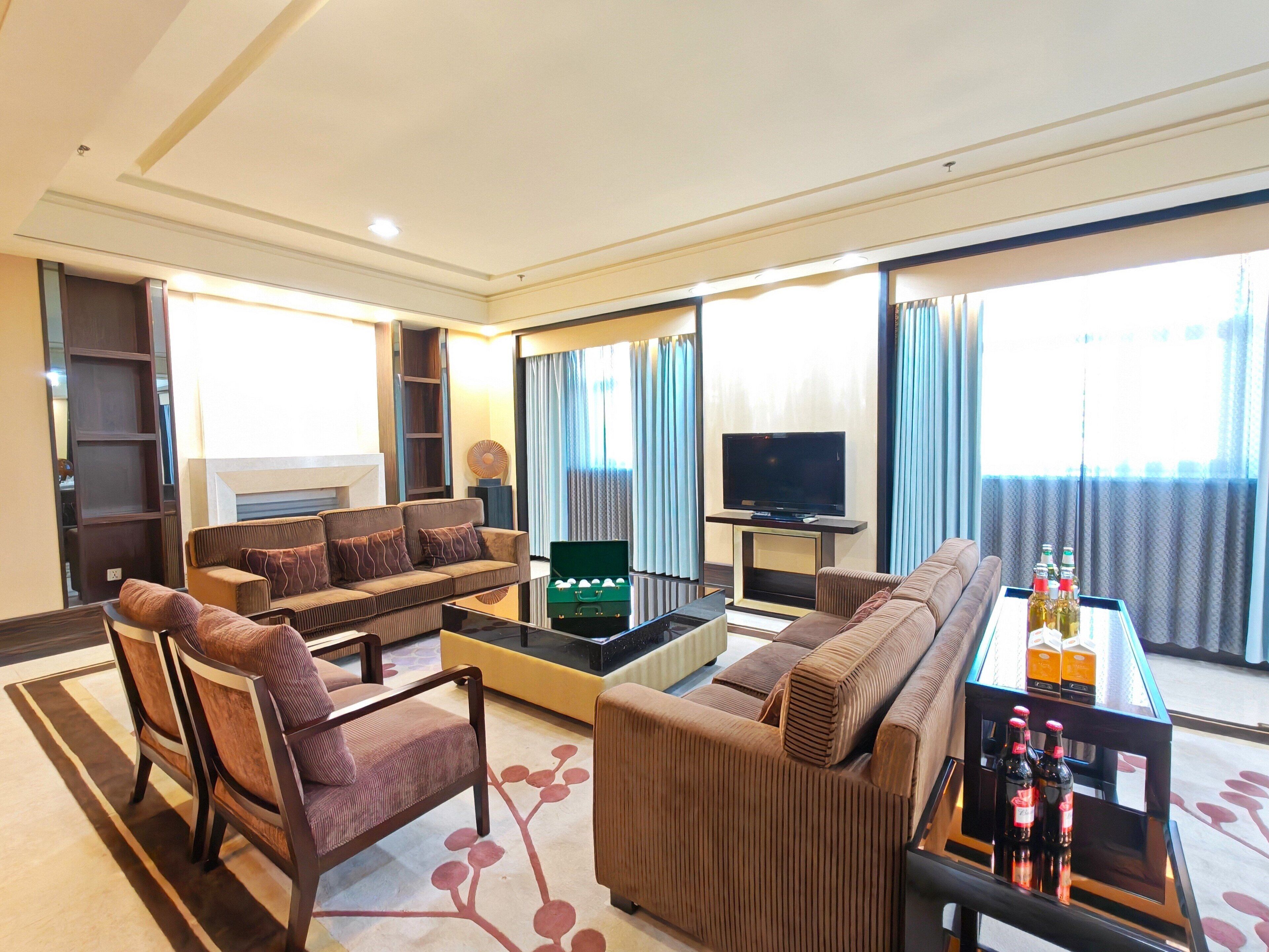 A modern living room with a sofa set, a coffee table, a television, and a minibar.