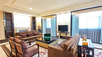 A modern living room with a sofa set, a coffee table, a television, and a minibar.