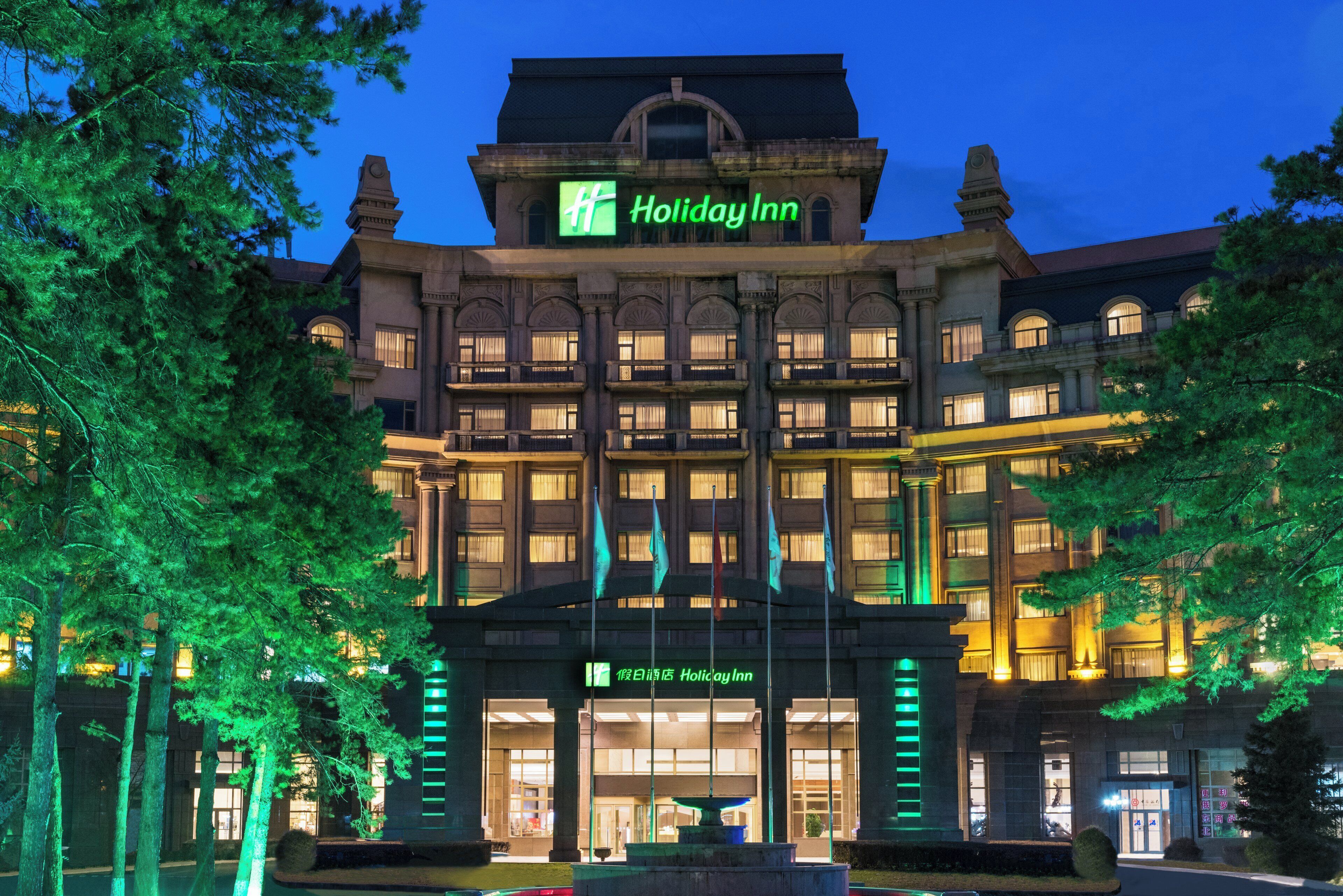 Un immeuble à plusieurs étages, surmonté d’une grande enseigne « Holiday Inn » bien visible.