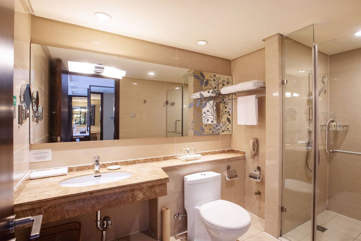 A modern bathroom with a glass-enclosed shower, a double sink vanity, and a toilet.