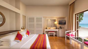 A hotel room with a bed, desk, chair, and a view of the beach.