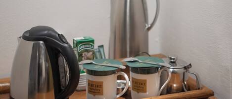 A tray with a coffee pot, two mugs labeled 'Heritage Tea Factory', a box of 'Ambewela' tea, and a silver teapot.