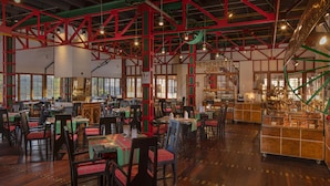 A spacious restaurant with high ceilings, exposed beams, and a variety of seating arrangements. - Heritance Tea Factory (Kandapola)