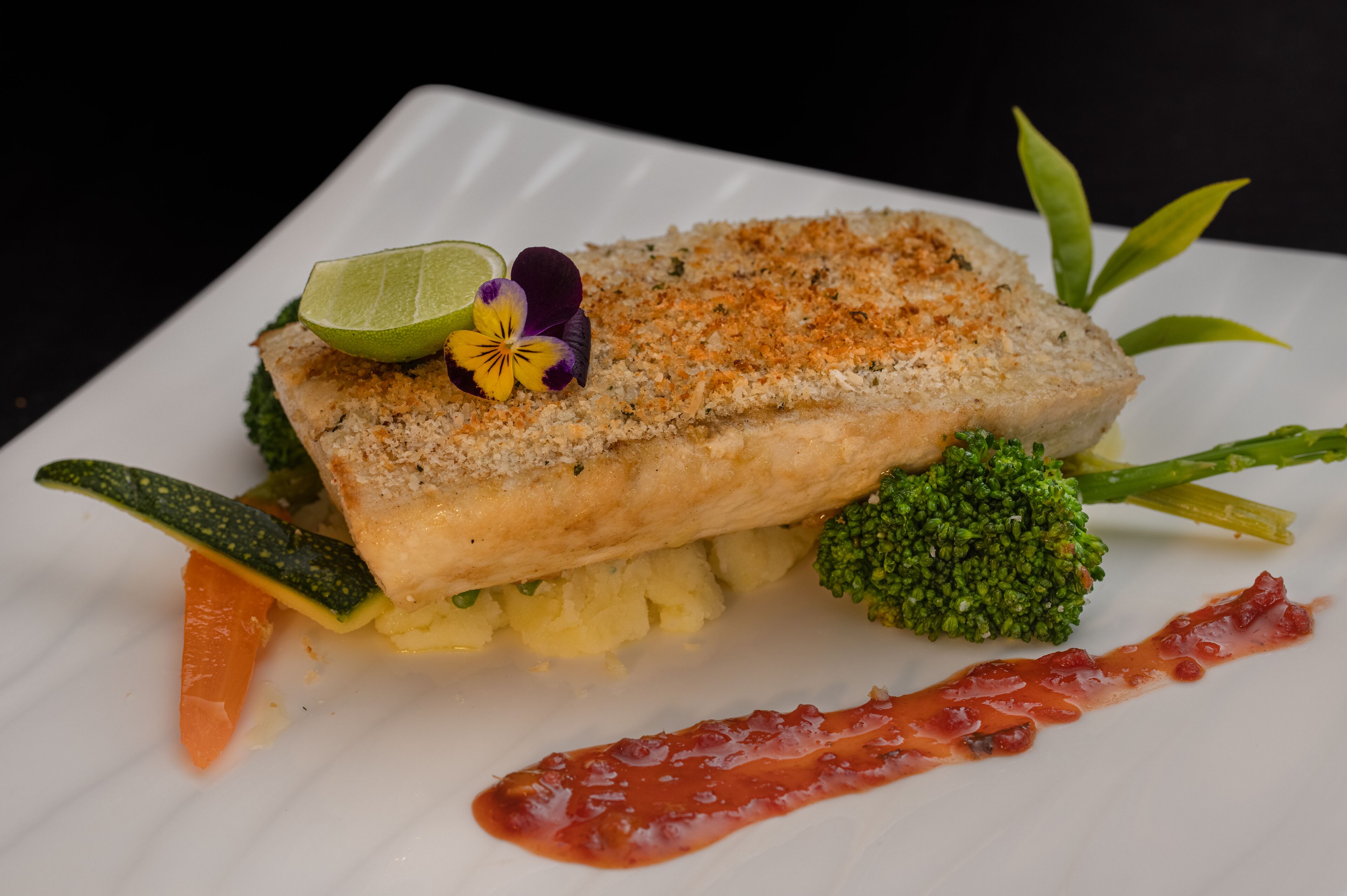 Ein angerichteter Teller mit Fisch, Brokkoli und einer Limettenspalte.