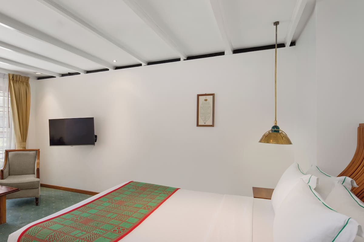 A hotel room with a bed, a chair, a television, and a framed certificate on the wall.