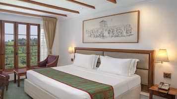 Une chambre d’hôtel avec un grand lit, un bureau, une chaise, un téléphone et un tableau au mur.