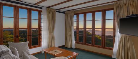 Una habitación con un ventanal grande, un sofá, una mesa y un televisor.