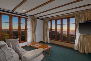 A room with a large window, a sofa, a table, and a TV.