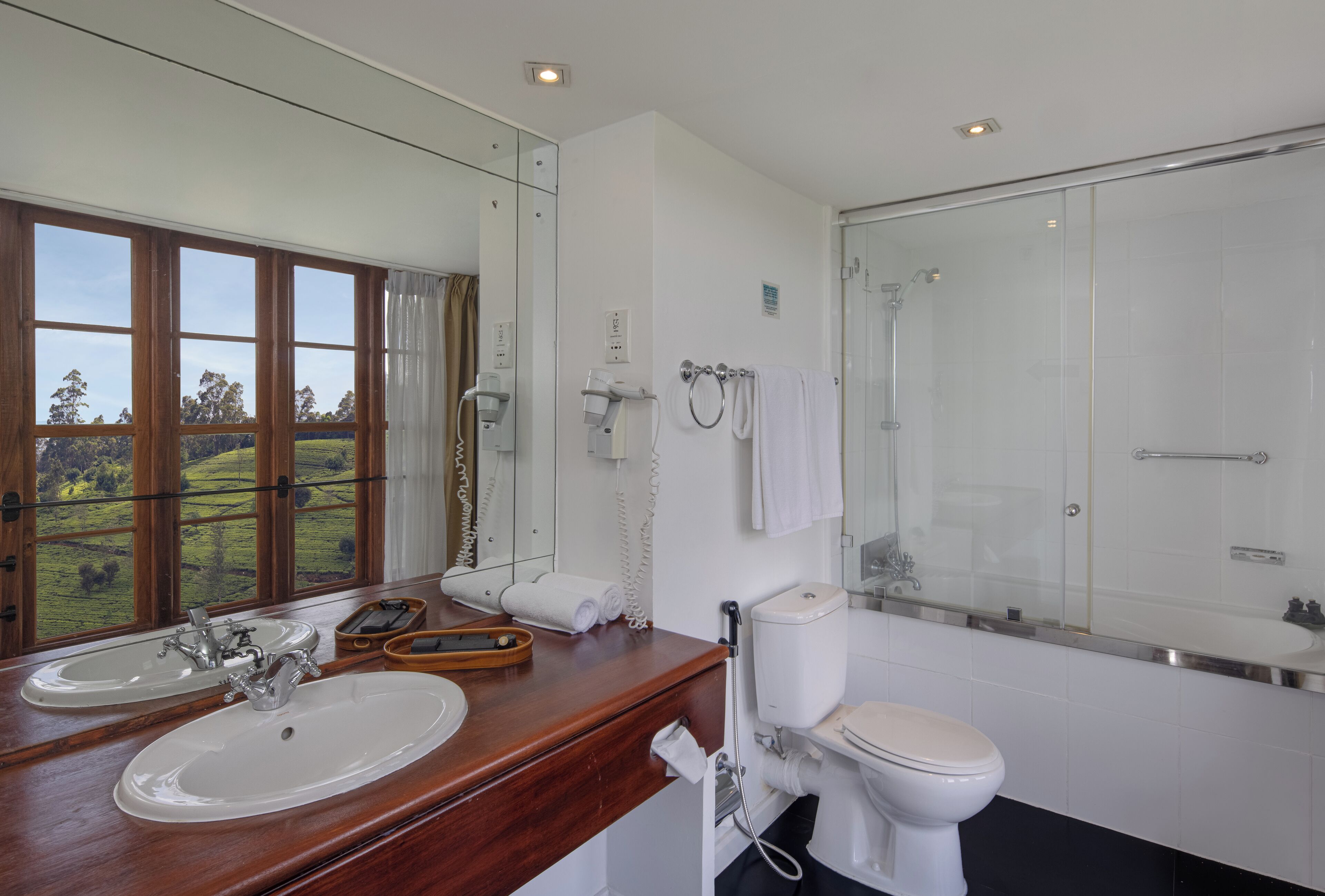 A bathroom with two sinks, a toilet, a shower, and a large mirror.