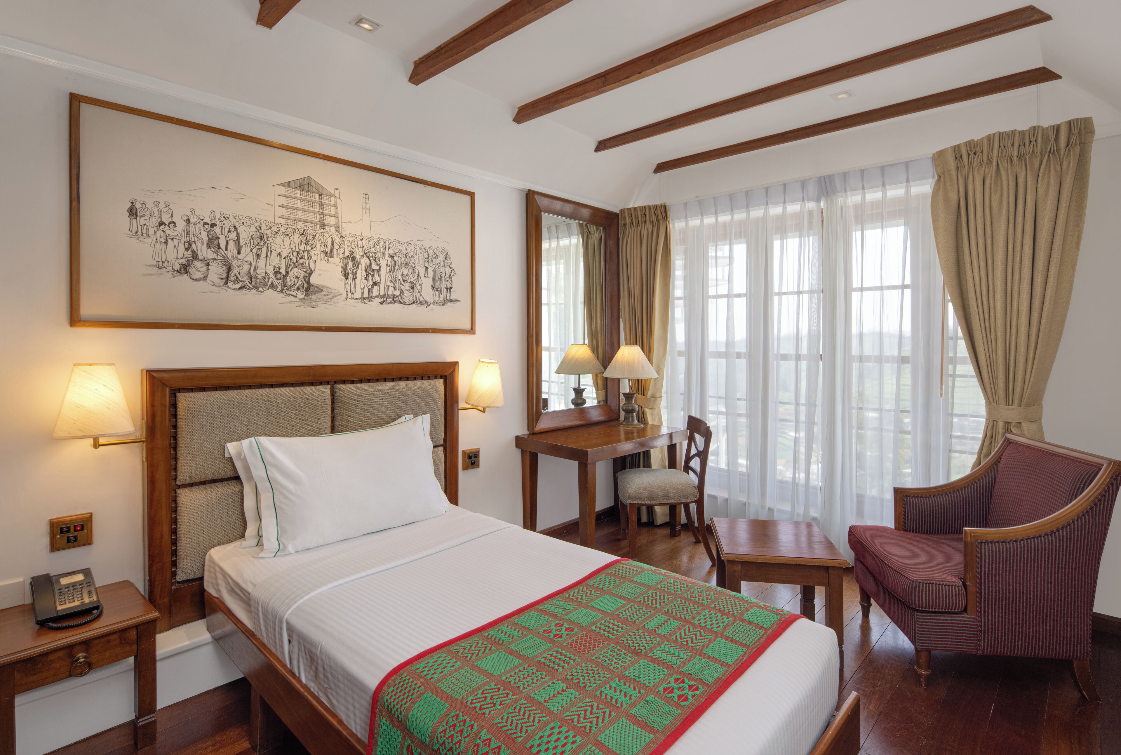 A hotel room with a large bed, a desk, a chair, and a painting on the wall.