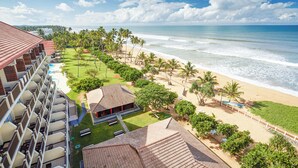 A hotel with multiple balconies overlooking a beach with palm trees and a pool. - Turyaa Kalutara (Wadduwa)