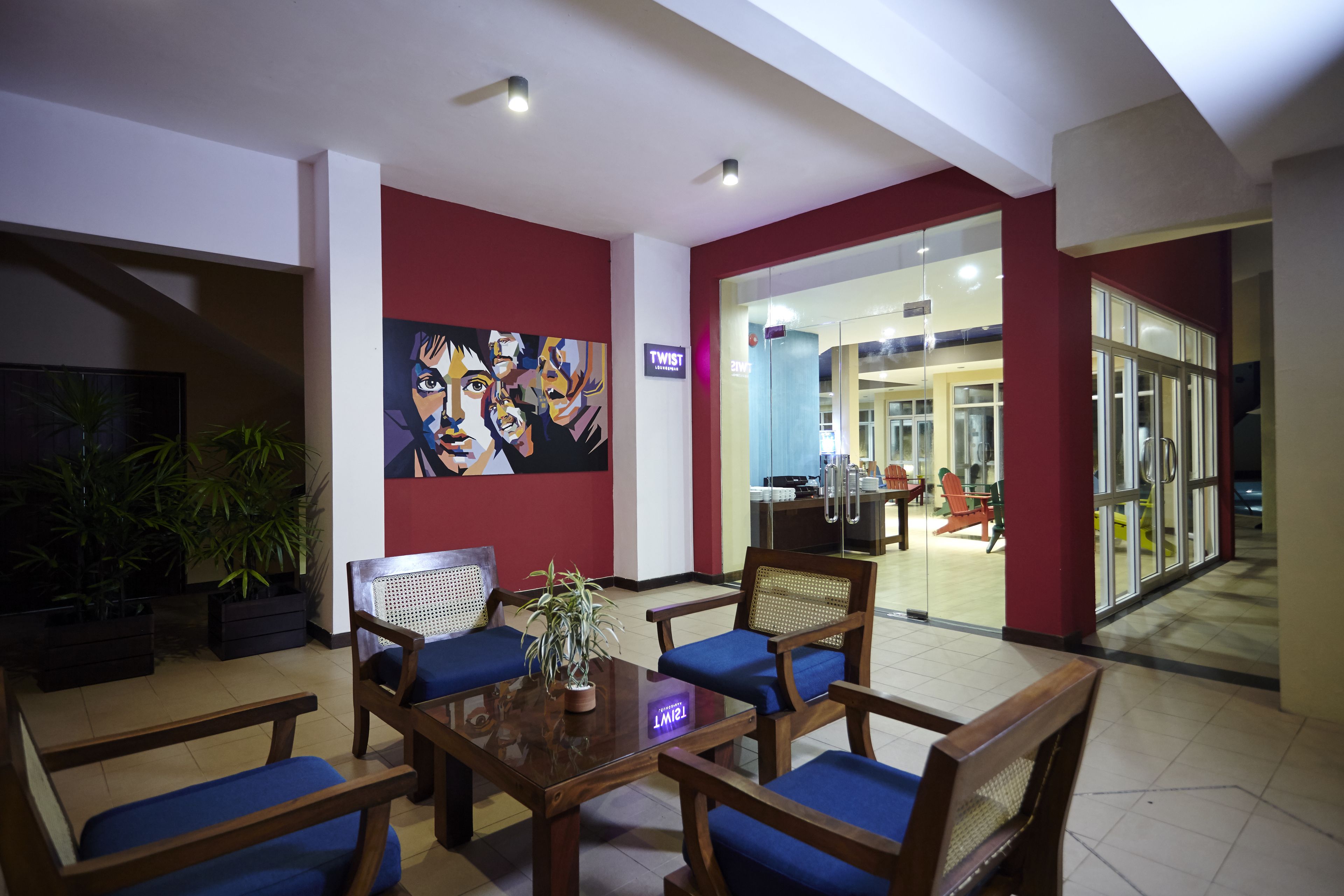 A lobby with a reception desk, seating area, and a large painting on the wall.