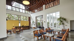 A spacious lobby with wooden furniture, a reception desk, and large windows offering views of palm trees. - Turyaa Kalutara (Wadduwa)