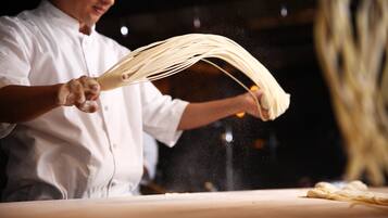 Una persona con delantal de chef blanco manipulando pasta, destacándose la pasta y las manos del chef.