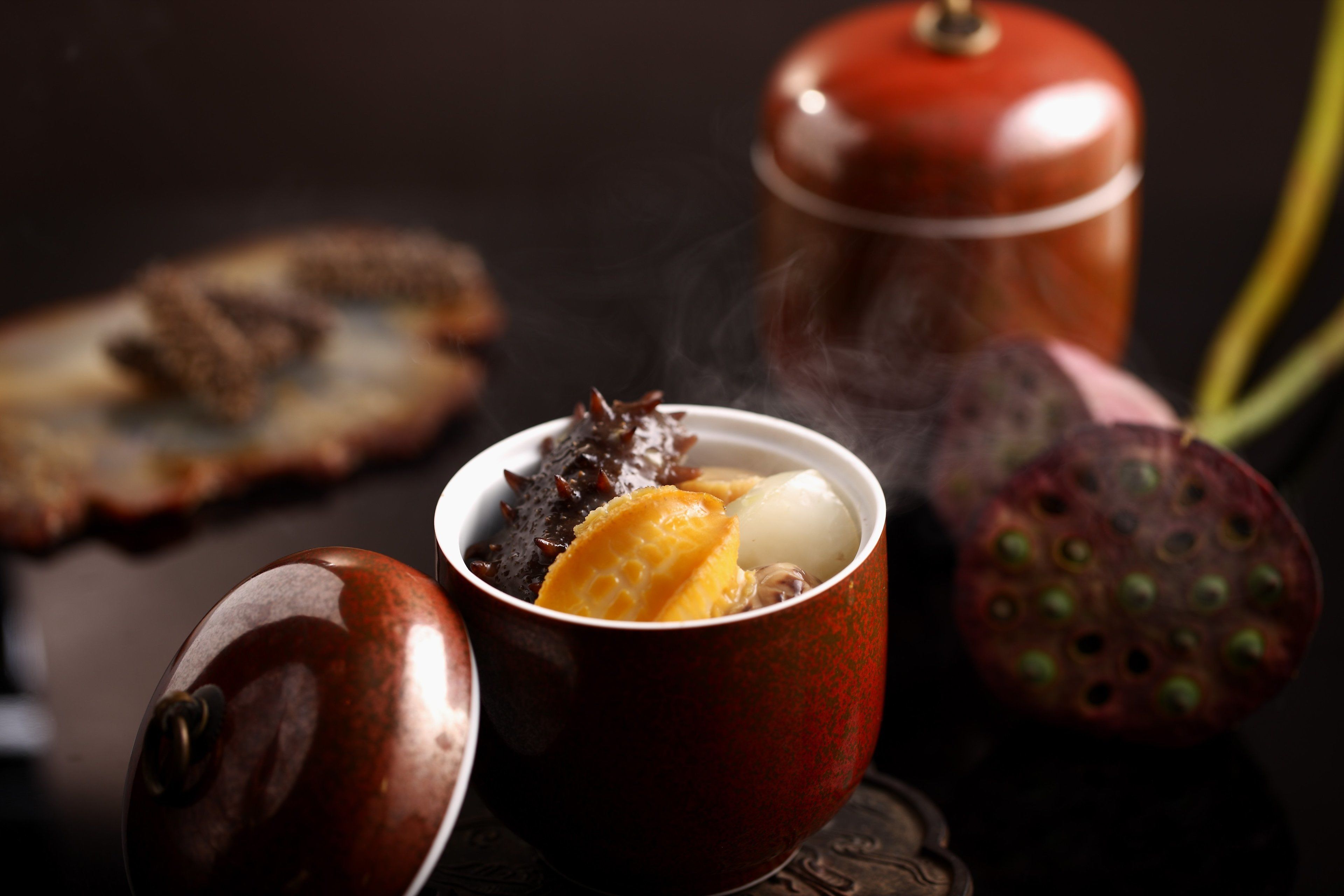 A traditional tea set with a teapot and cups, a piece of bread, and a fruit.