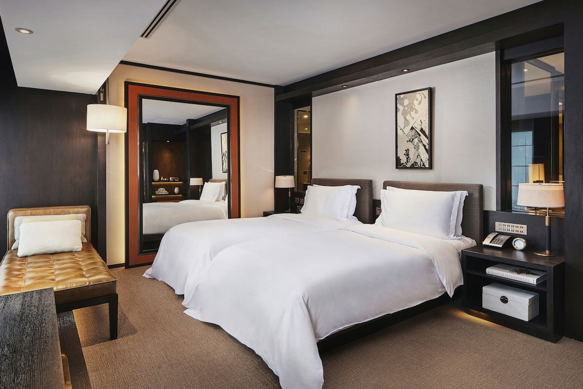 A hotel room with a large bed, bedside tables, a desk, and a chair.
