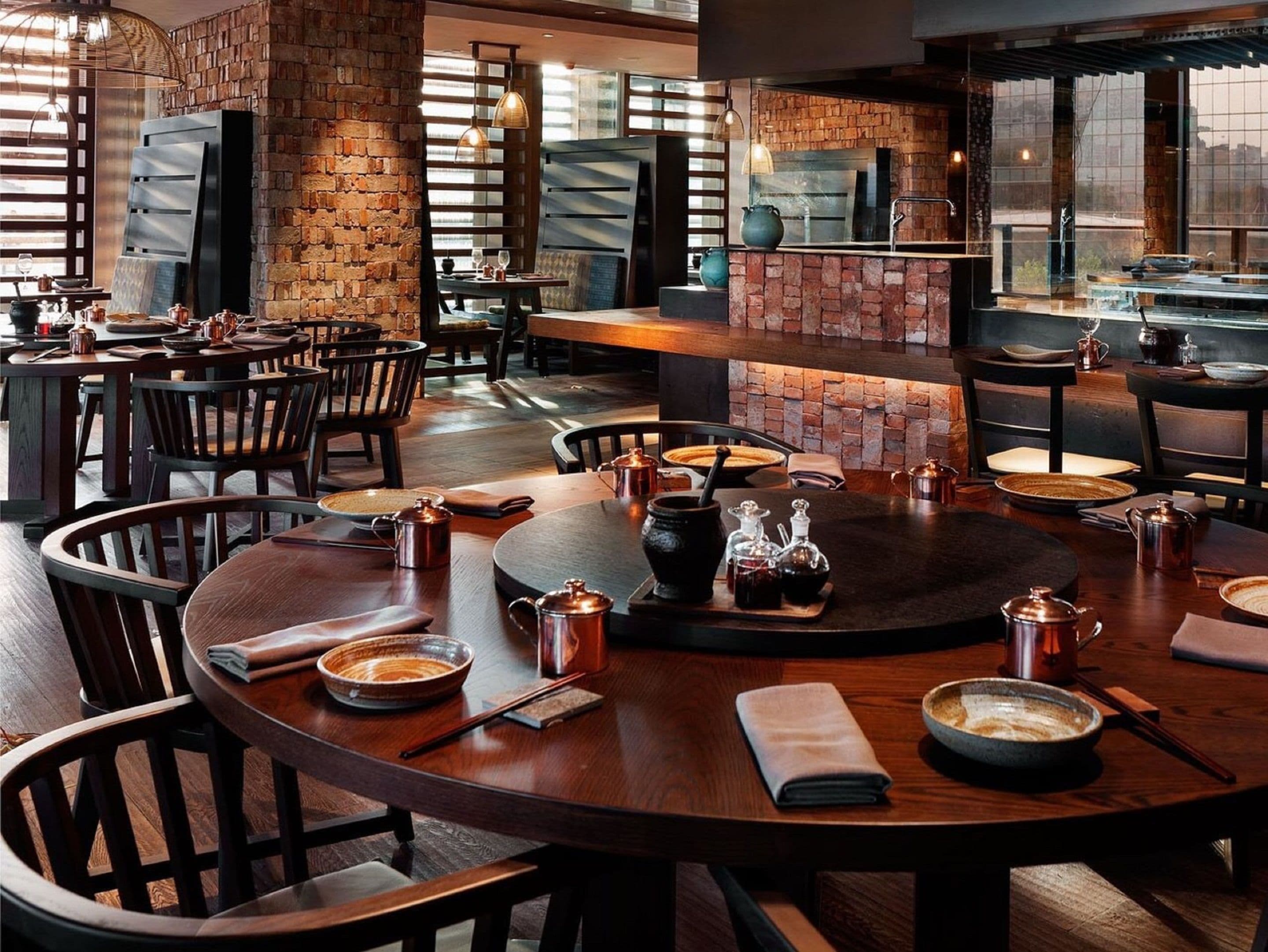 Un restaurante con paredes de ladrillo, mesas y sillas de madera.