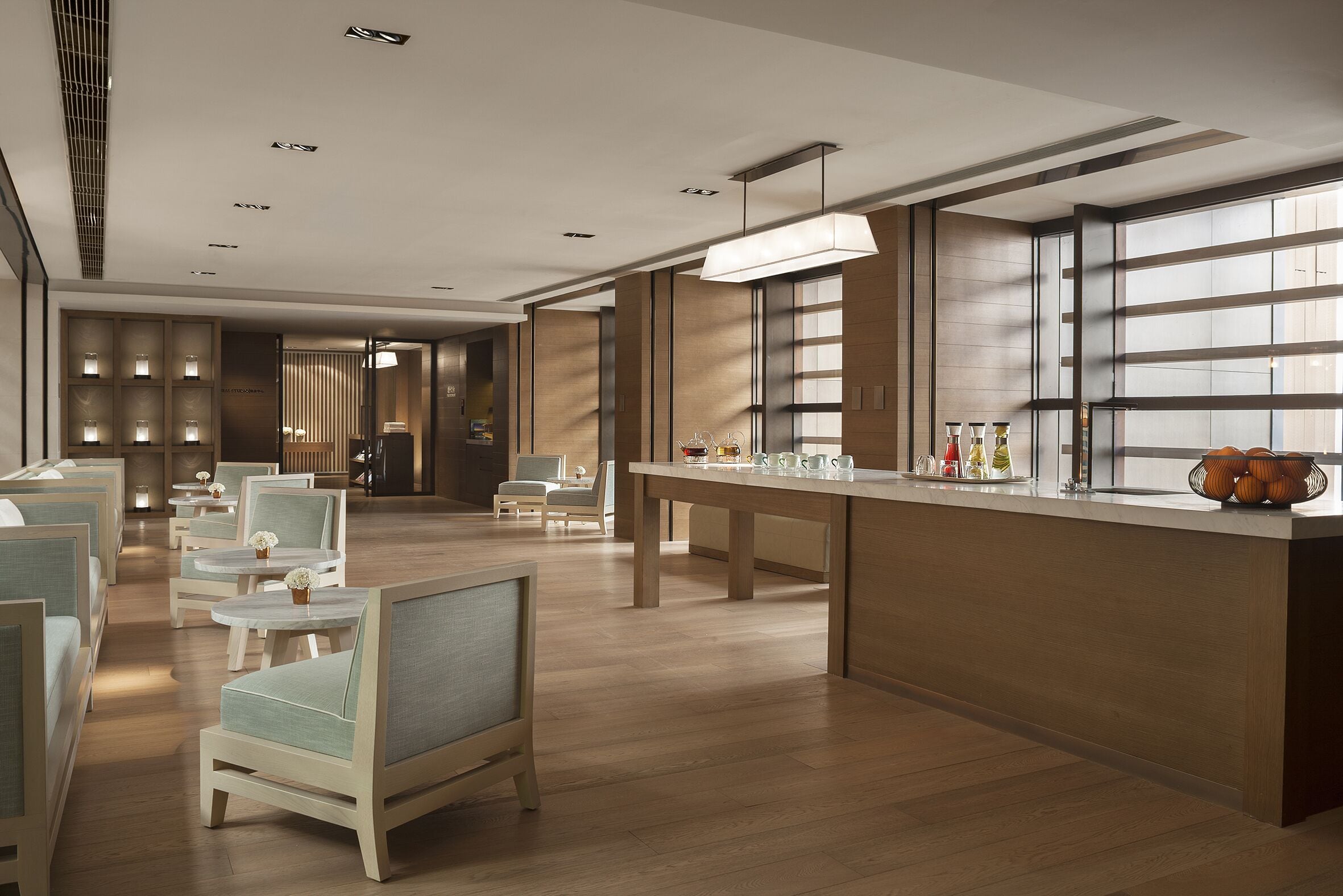 Eine moderne Hotelhalle mit Sitzbereichen, einem Empfangsbereich und großen Fenstern.