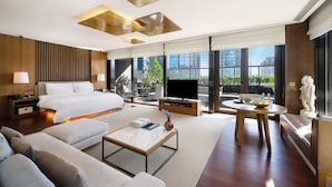 A modern hotel room with a large bed, a TV, a sofa, a coffee table, and a statue. - Rosewood Beijing (Beijing)