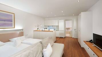 Una habitación de hotel moderna con cama, sofá, televisor y kitchenette.