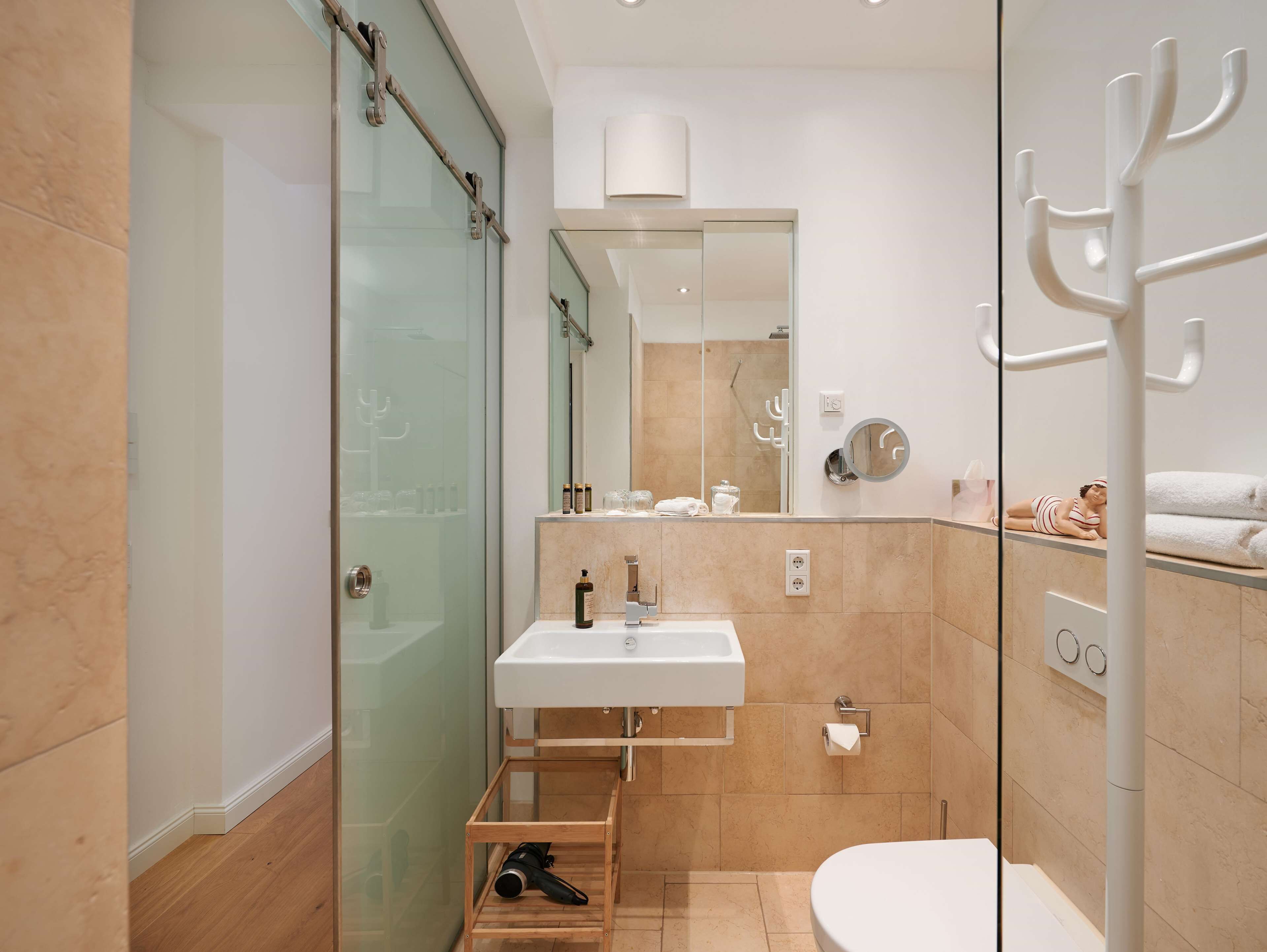 A modern bathroom with a glass shower enclosure, a white sink, and a toilet.