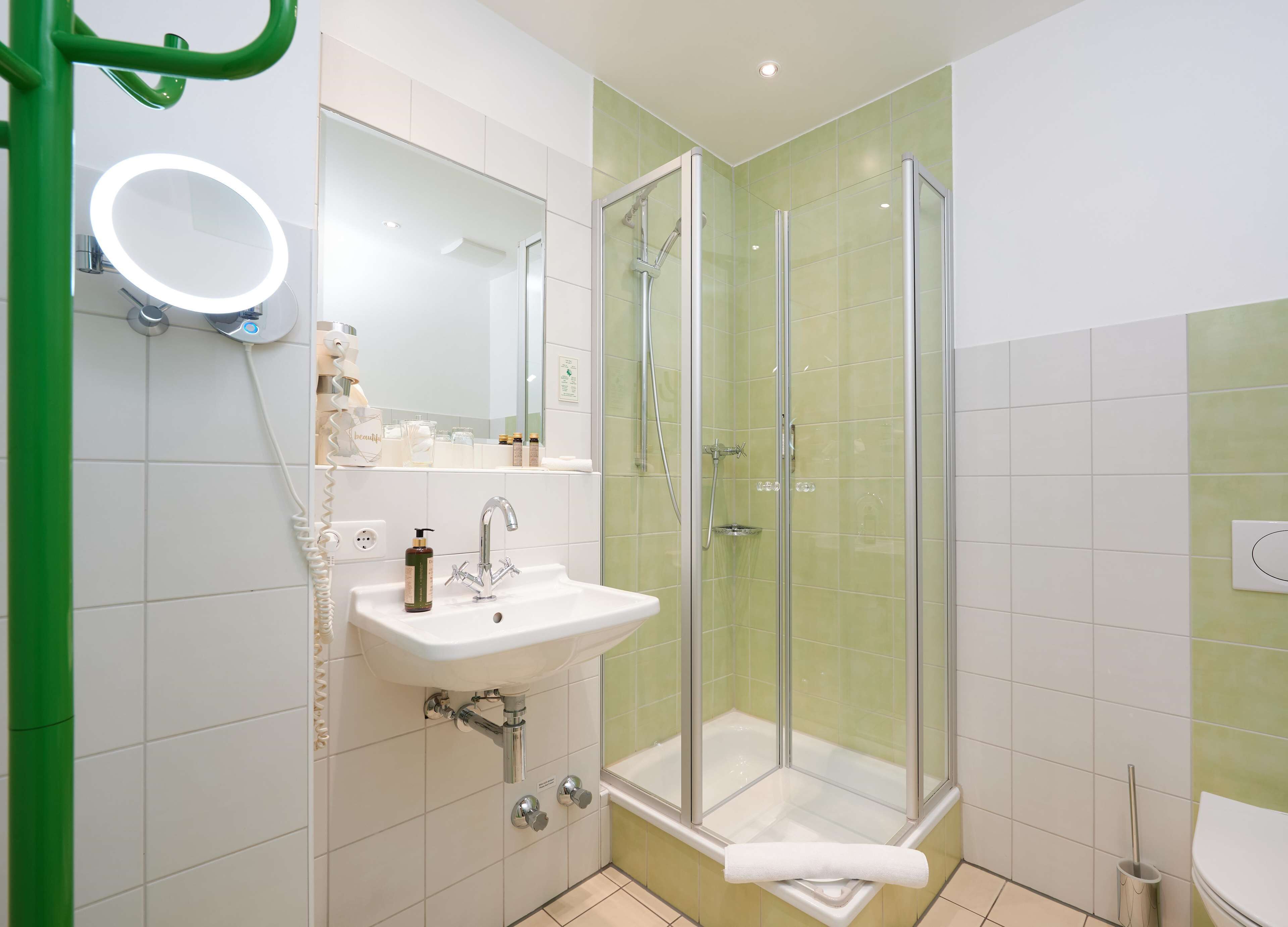 A bathroom with a glass-enclosed shower, a sink with a mirror above it, and a toilet.