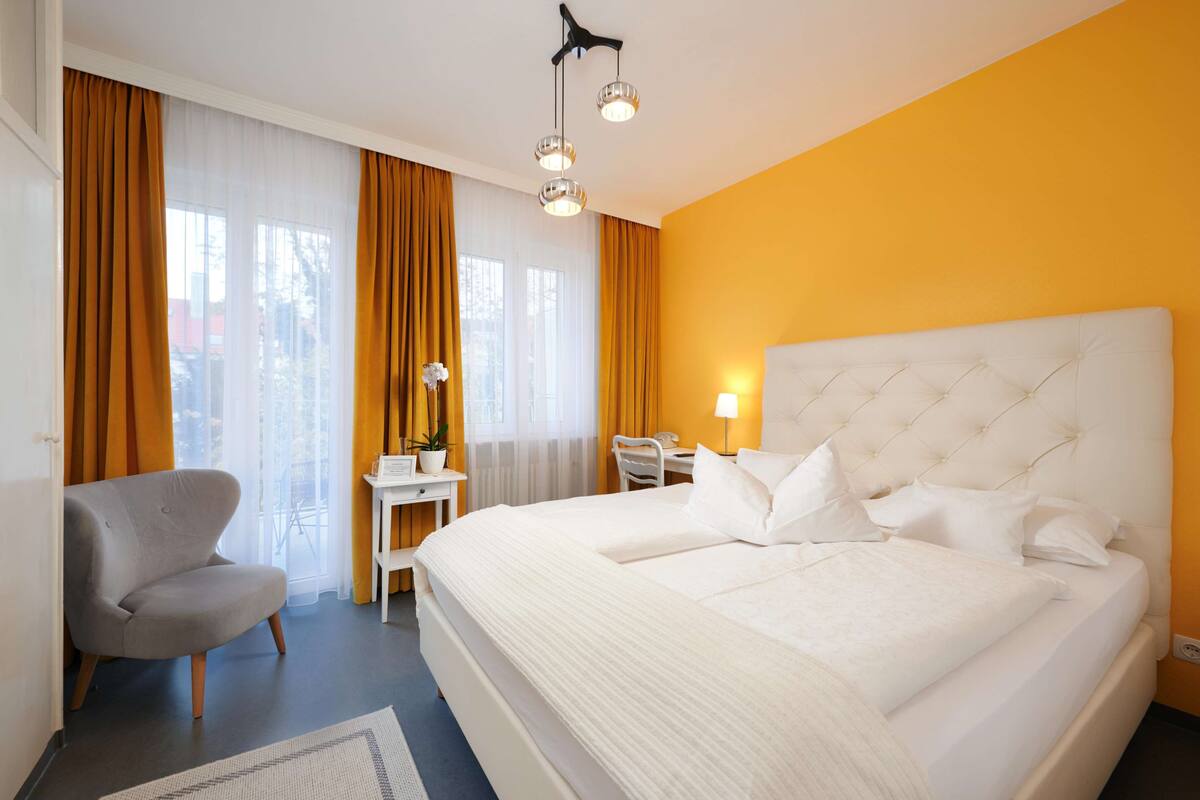 A hotel room with a large bed, a desk, a chair, and a sofa.