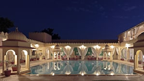 A pool area with a reflection, surrounded by traditional architecture and potted plants. - Rohet Garh (Rohat)